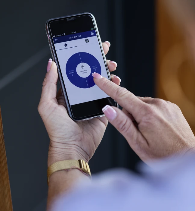 Caméra de surveillance extérieure blanche montée sur mur de bâtiment, ciel bleu en arrière-plan