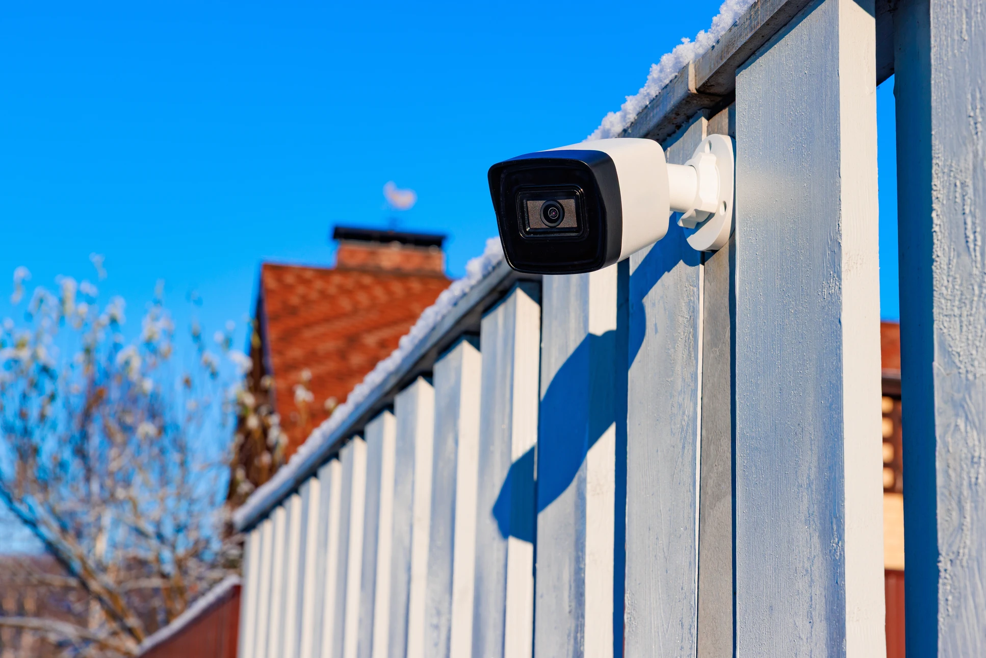 Caméra de vidéosurveillance blanche montée sur poteau extérieur, orientée vers la droite